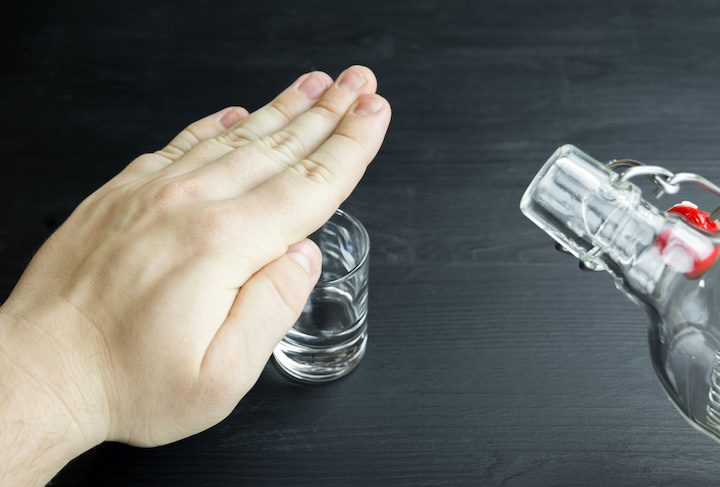 Person holding their hand over a shot glass indicating they want to stop drinking alcohol or cutting back on alcohol consultion