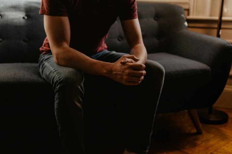 Man sitting on a couch with hands folded during a therapy session for mental wellness