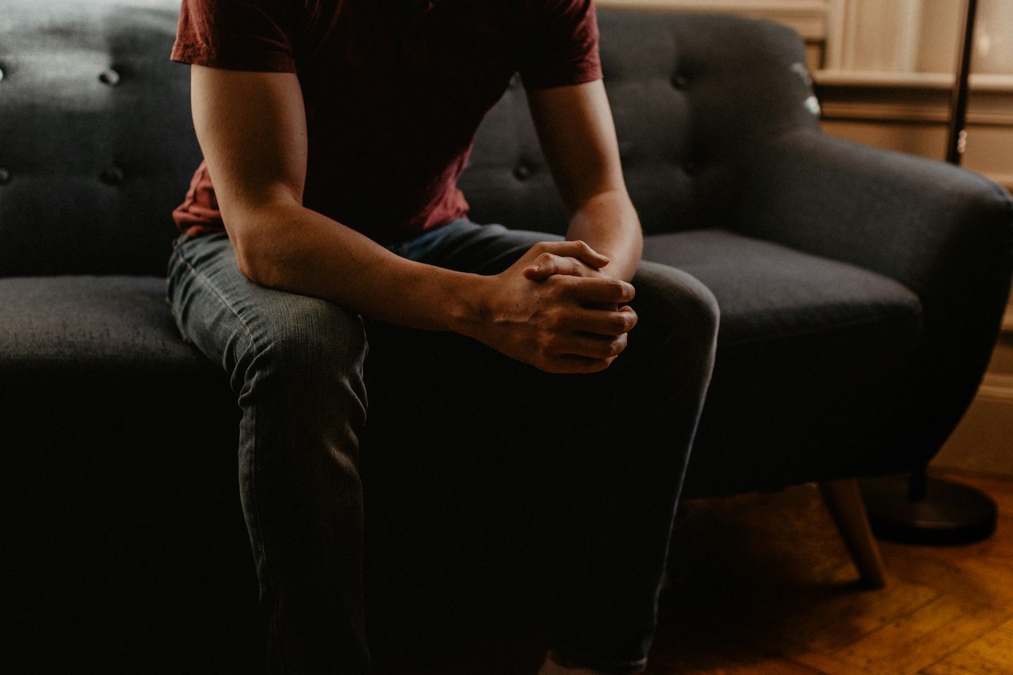 Man sitting on a couch with hands folded during a therapy session for mental wellness