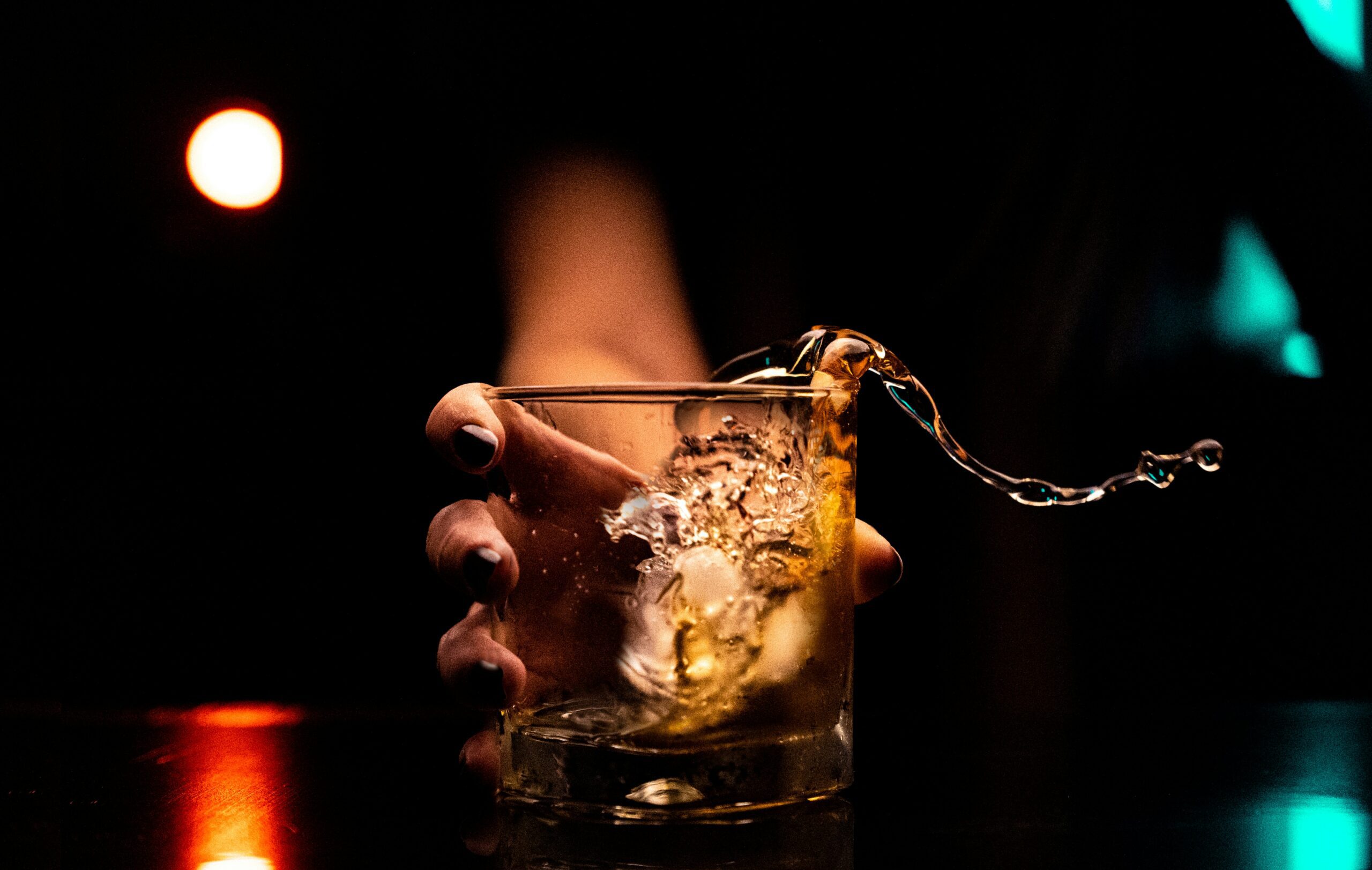 person holding a whiskey glass with dim lighting, symbolic of drinking culture