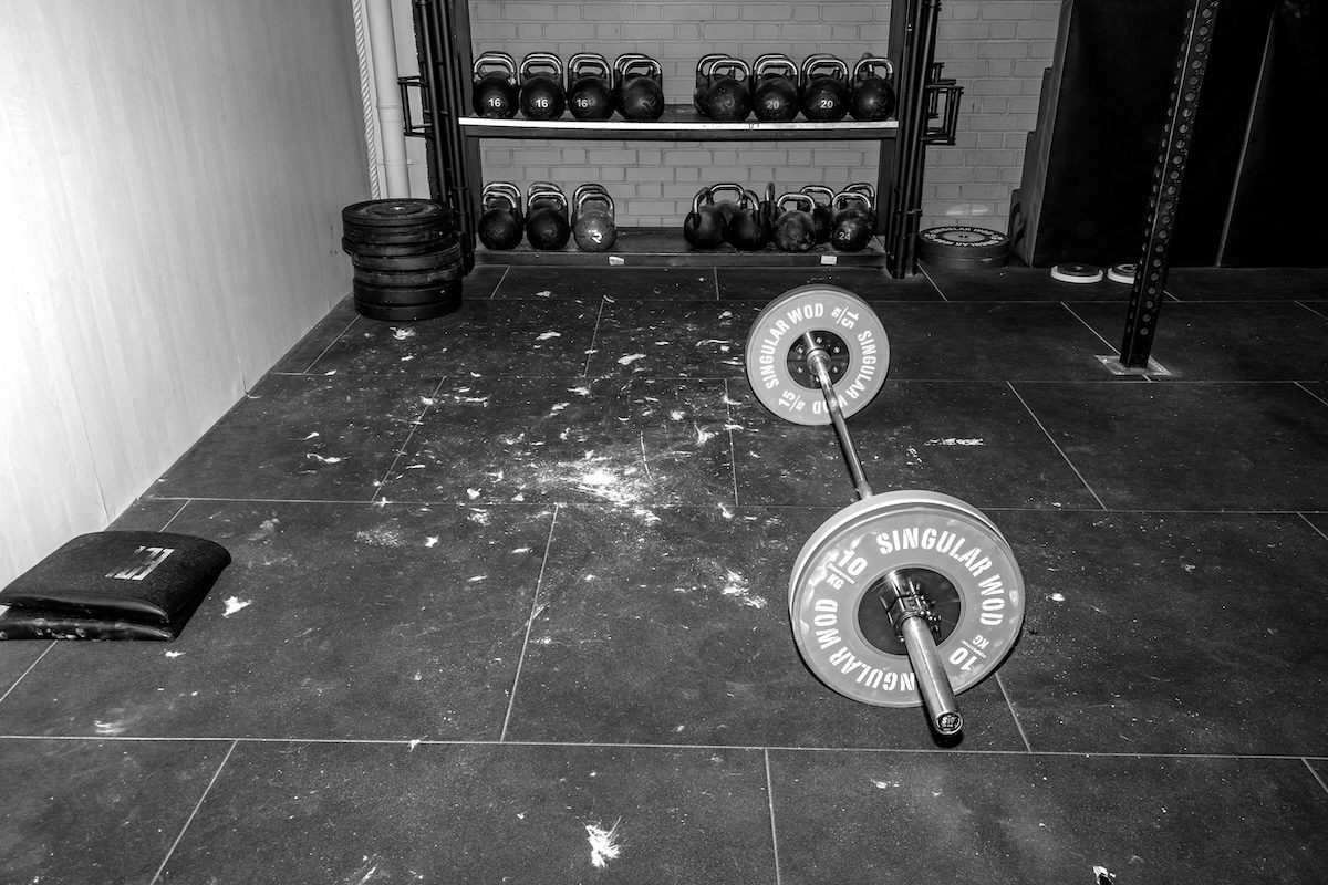 "CrossFit gym interior with barbells, weight plates, and functional training equipment, showing a typical setup for strength and conditioning workouts."