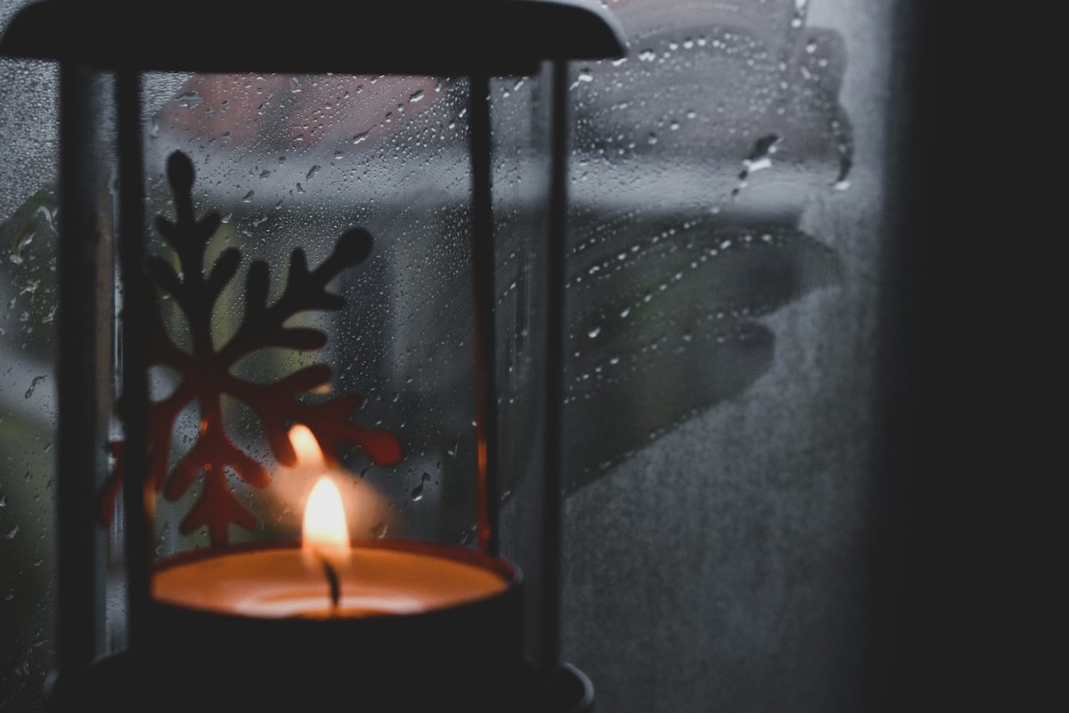 Candle in rainy window, signifying loss and grief