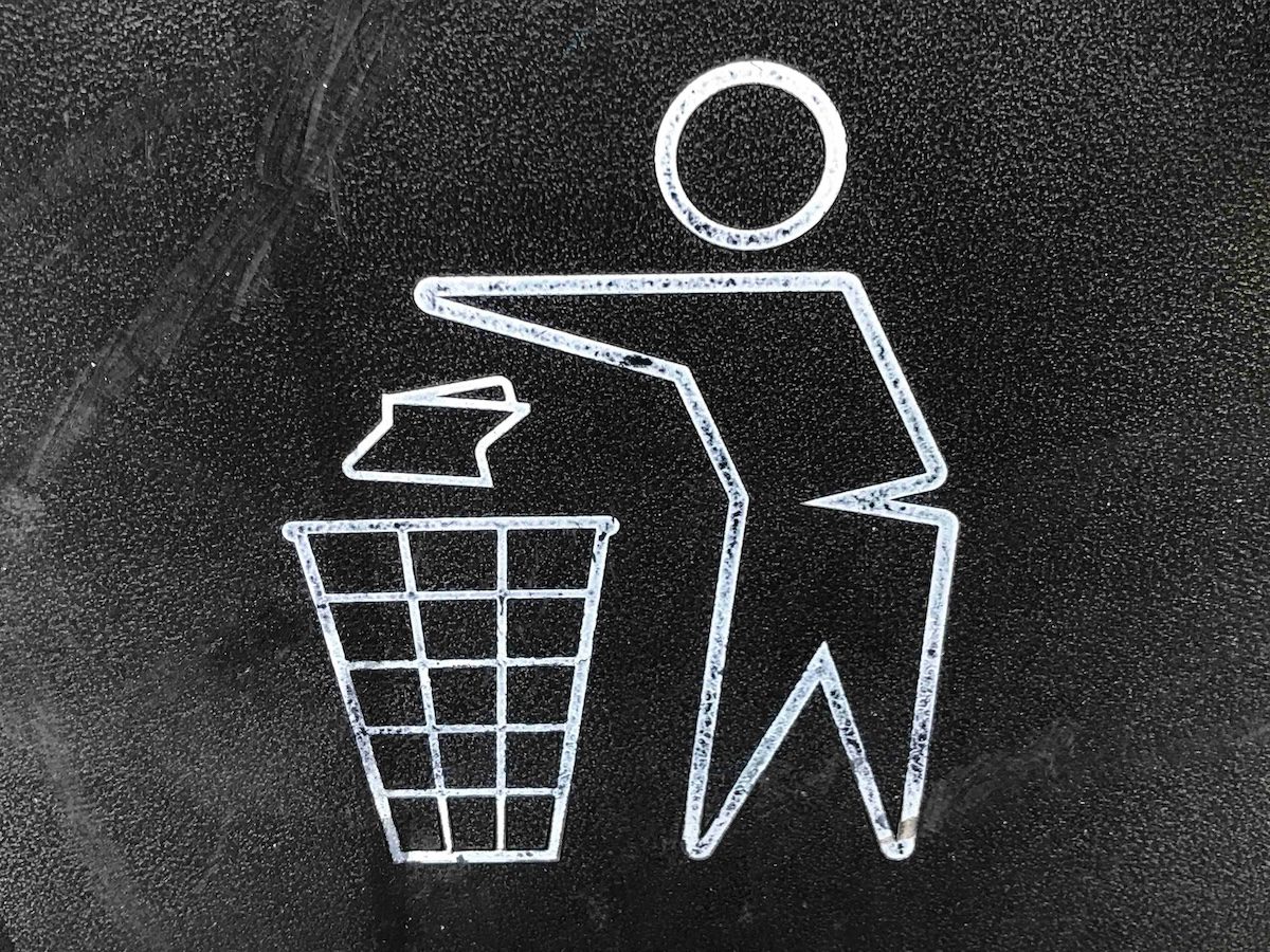 Line drawing of a person throwing paper into a trash bin, representing tossing out old goals or expectations.